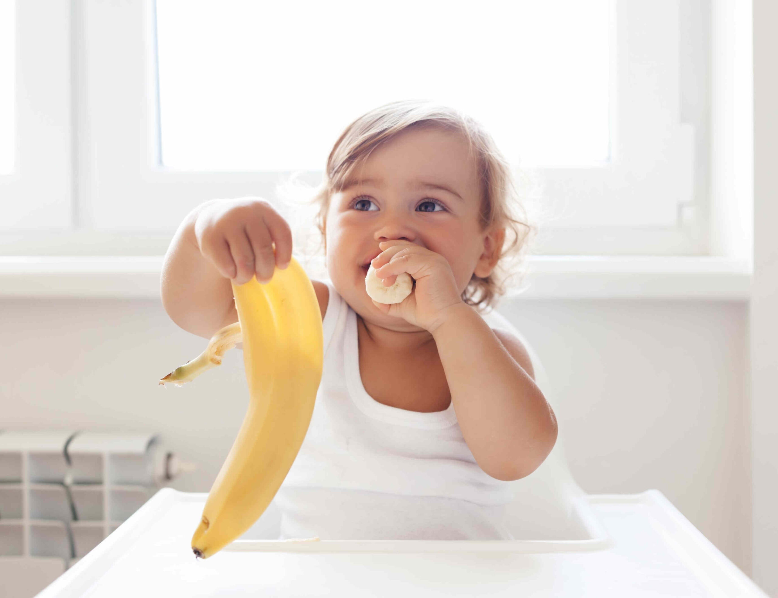 Baby eating banana with hands.