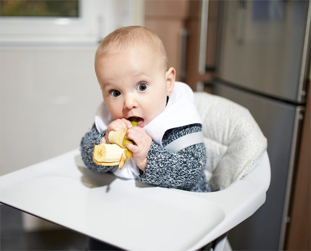 Baby eating half a banana.