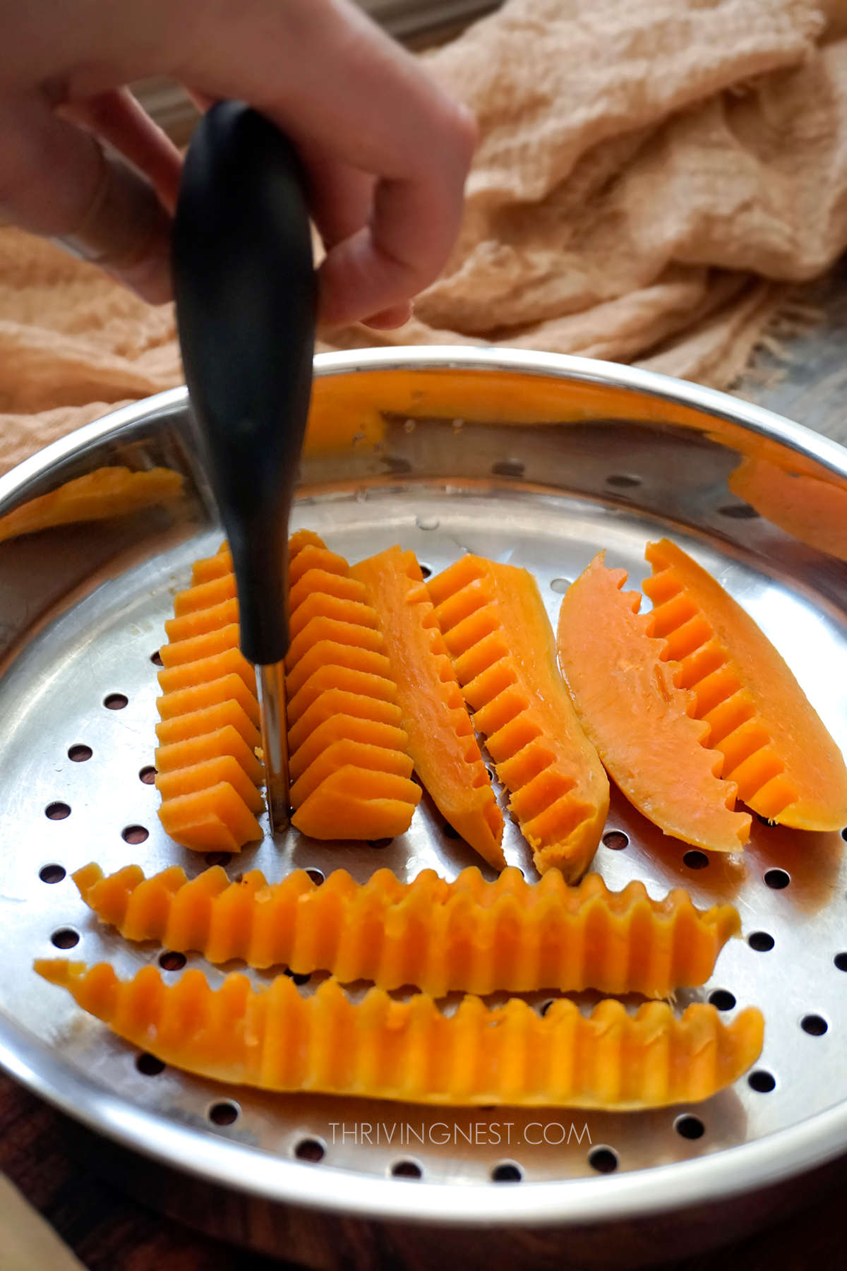 Cutting steamed sweet potato with crinkle cutter.