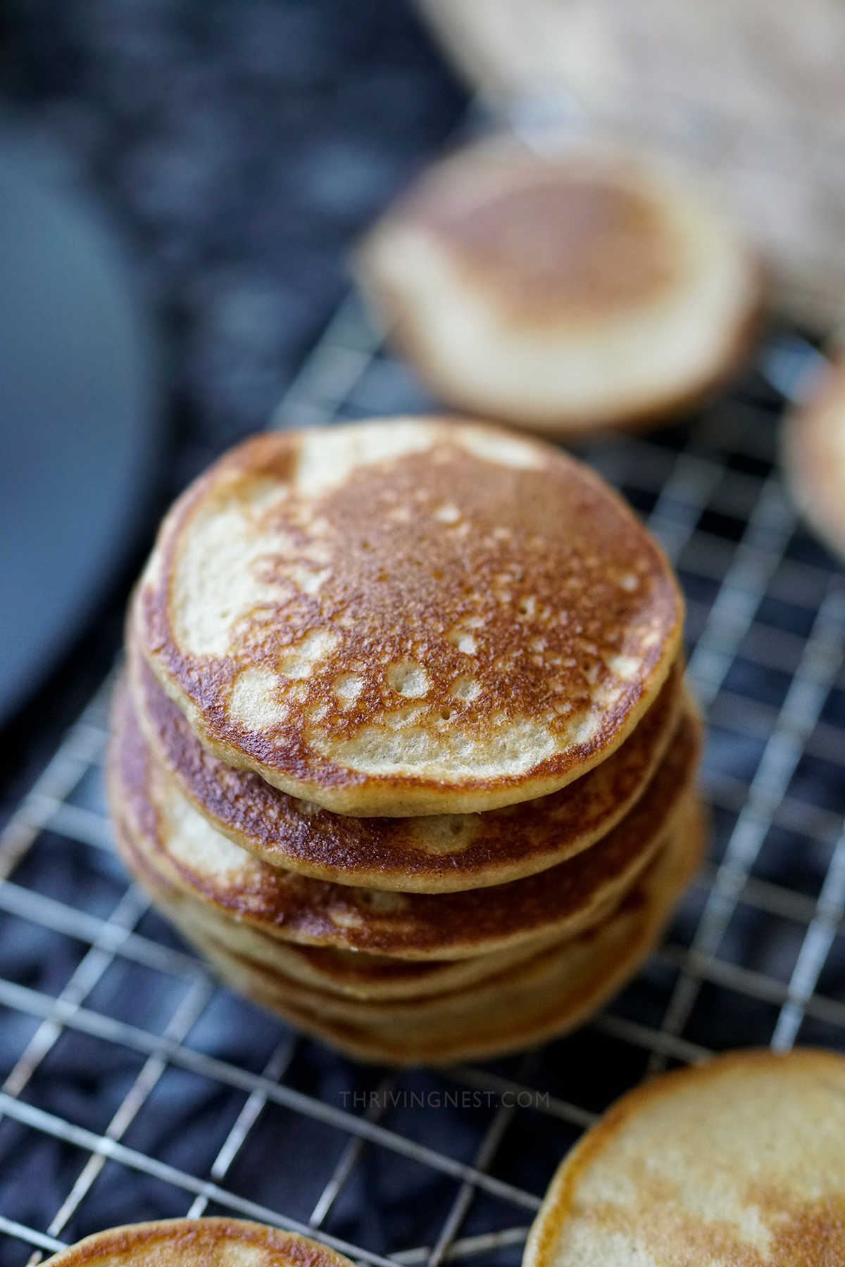 Soft banana oat pancakes for baby stacked on a wire rack.