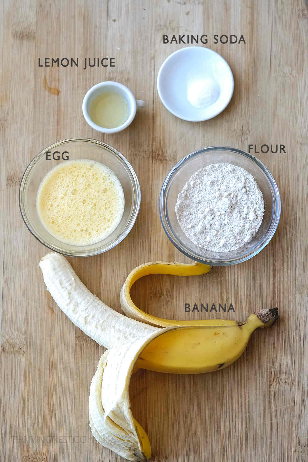 Ingredients for baby banana pancakes displayed on a board.