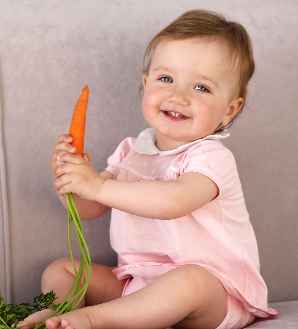 Baby holding a carrot.